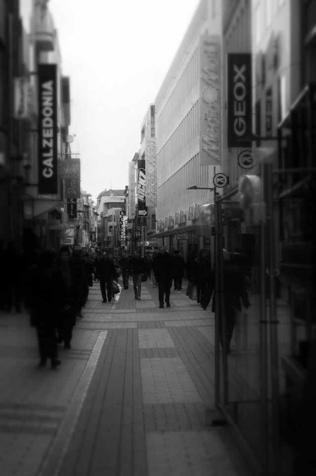 architecture, building exterior, built structure, city, large group of people, street, city life, walking, text, men, person, city street, transportation, communication, western script, building, road, non-western script, outdoors