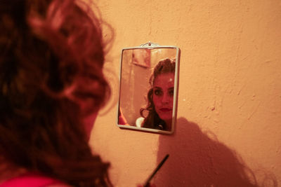 Portrait of teenage girl photographing against wall