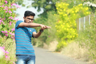Full length of young man standing against pink flowering plants