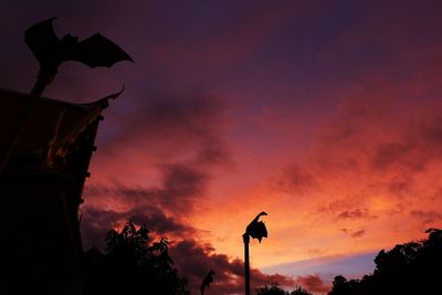 Low angle view of silhouette street light against orange sky