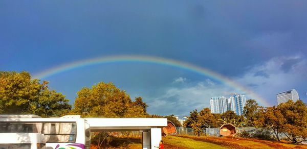 Rainbow over buildings in city against sky