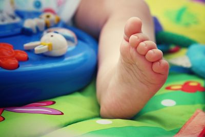 Low section of baby with toy on bed