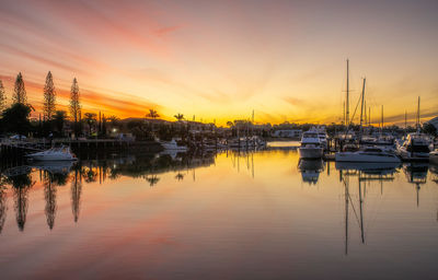 Sailboats moored at harbor during sunset