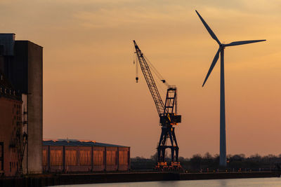 Cranes at construction site against sky during sunset