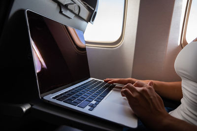 Midsection of man using mobile phone in airplane