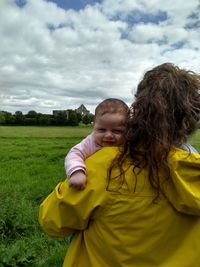 Portrait of cute girl relaxing on field against sky