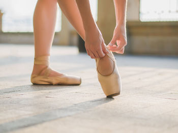 Low section of ballet dancer tying shoe