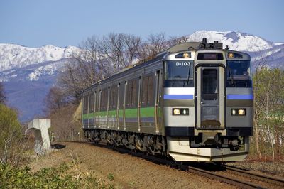 Clear blue sky, snow mountain and rapid train niseko liner