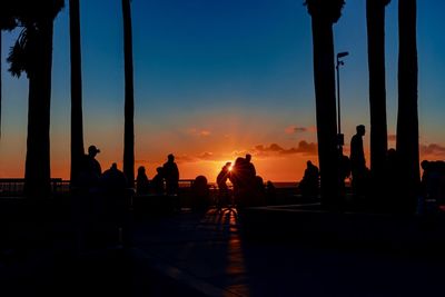 Silhouette people by sea against sky during sunset