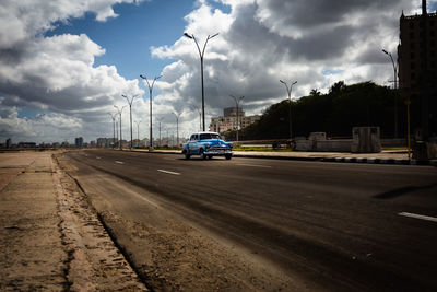 Cars on street in city against sky