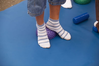 Low section of child wearing socks standing on spiked balls while exercising in gym