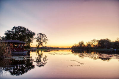 Scenic view of lake against clear sky at sunset