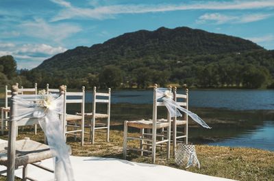 Chairs by lake against mountains