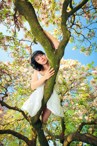 Portrait of smiling young woman standing against tree