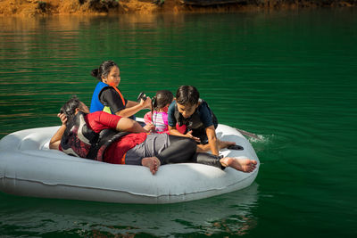 Family wearing life jackets paddling on an inflatable boat in kenyir lake, malaysia.