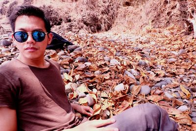 Portrait of man with sunglasses on rock during autumn