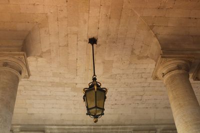 Low angle view of illuminated lamp hanging on ceiling of building