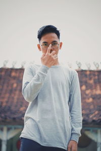 Portrait of young man standing against clear sky