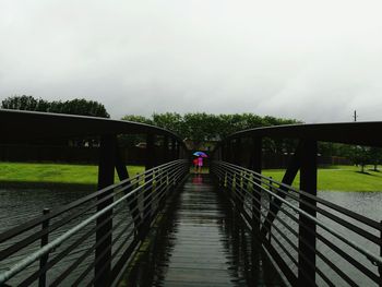 Footbridge over river against sky