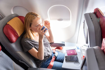 Midsection of woman holding camera while sitting in airplane