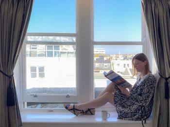 Woman sitting in glass window at home