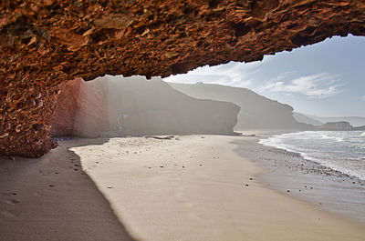 Rock formation on beach against sky