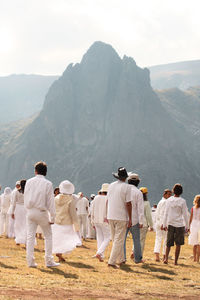 Rear view of people standing on mountain against sky