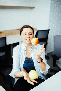 A woman throw up apples in the office, healthy eating at work