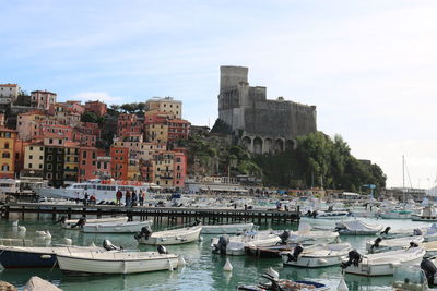 Boats moored in harbor against buildings in city