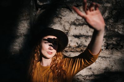 Portrait of young woman in hat standing against wall