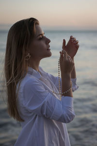 Side view of woman standing at beach during sunset