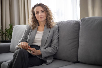 Portrait of young woman sitting on sofa at home