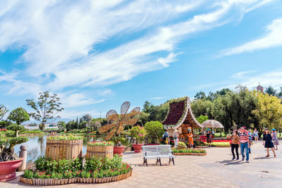 Group of people in park against cloudy sky