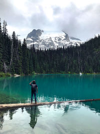 Rear view of man standing by lake against sky