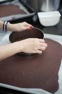 Cropped image of woman using pastry cutter over cake at kitchen