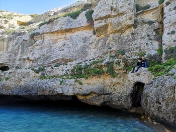 Rear view of man on rock by water