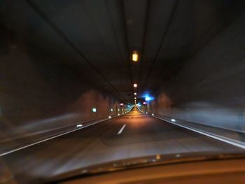 Illuminated tunnel seen through car windshield