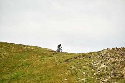 Man riding bicycle on mountain against sky