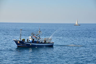 Ship sailing on sea against clear sky