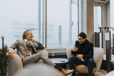 Happy male delegates discussing strategy against window