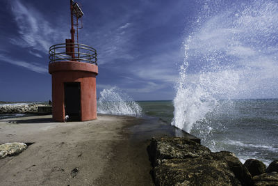 Lighthouse by sea against sky