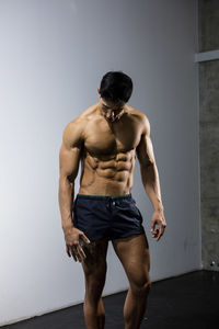 Shirtless muscular man standing against wall