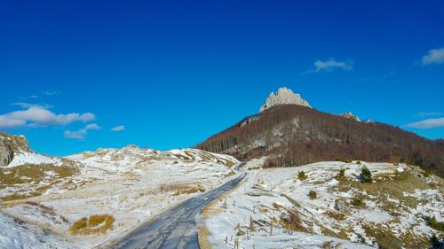 Scenic view of snowcapped mountains against blue sky