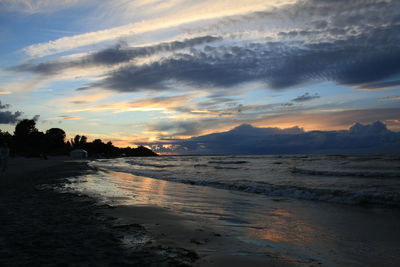 Scenic view of beach against sky at sunset