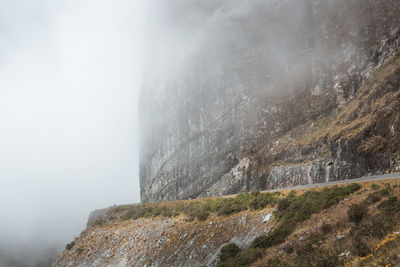 Low angle view of rocky mountain in foggy weather