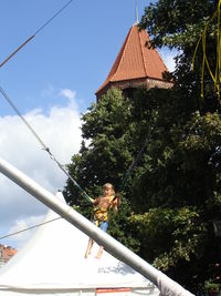 Rear view of smiling girl on tree against sky