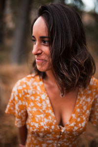 Close-up of smiling young woman looking away standing in forest