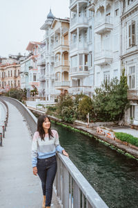 Portrait of woman standing in canal in city