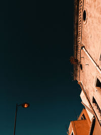 Low angle view of illuminated street light and buildings against sky