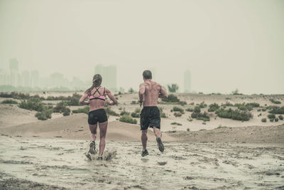 Rear view of people running on land against clear sky